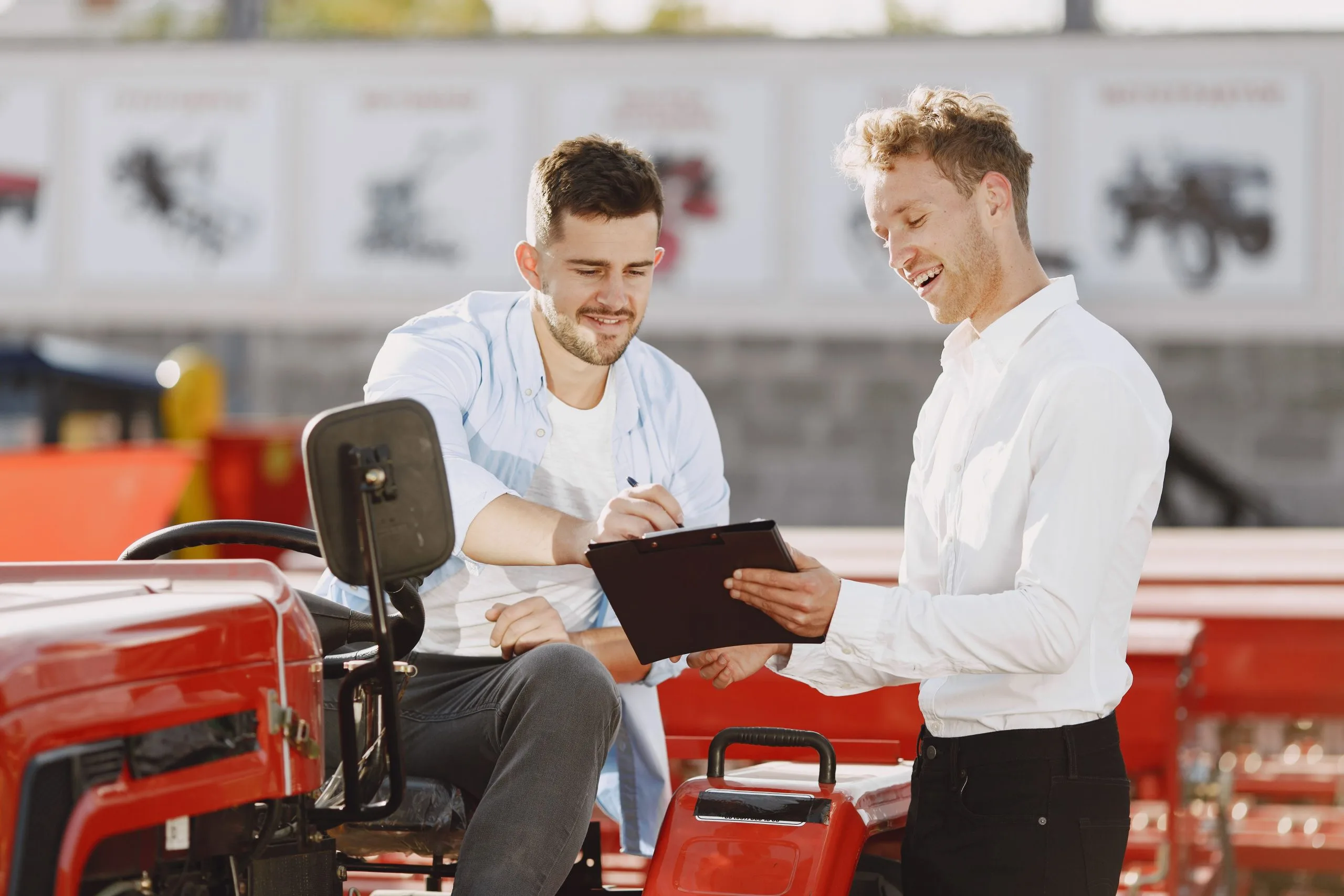 Two men discussing asset based equipment financing while seated on a tractor outdoors