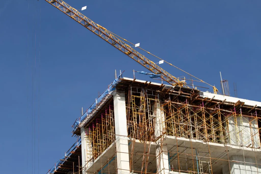 Construction financing supports projects like the building under scaffolding with a crane above against a clear blue sky