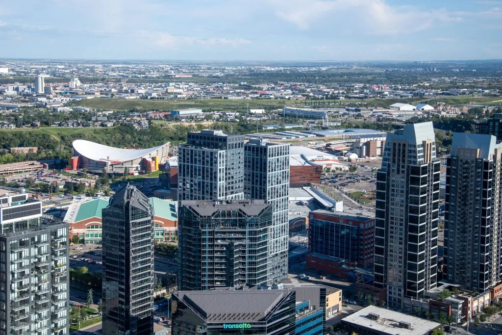 A panoramic view showcases urban buildings against a distant landscape and blue sky